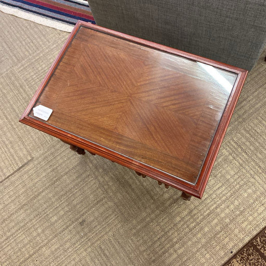 Wooden coffee table with glass top on a carpeted floor