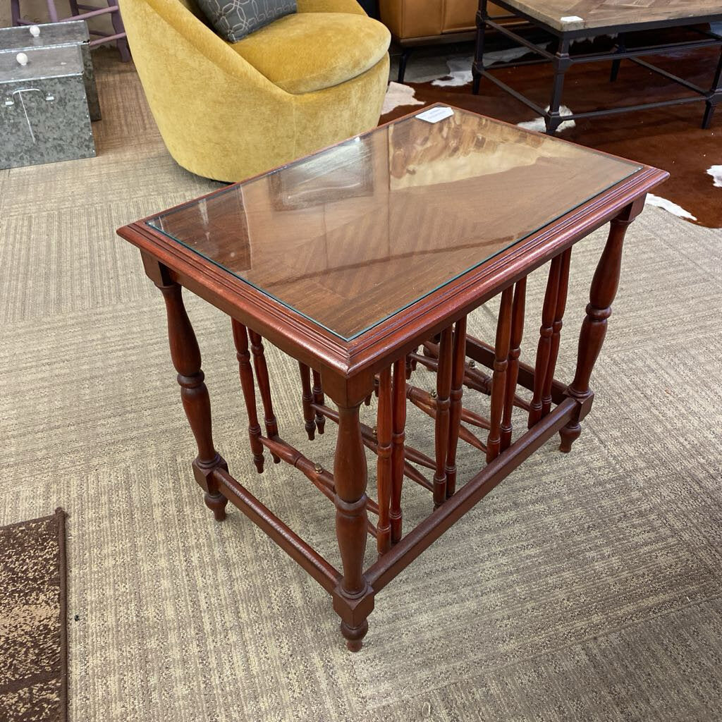 Wooden side table with glass top on a carpeted floor