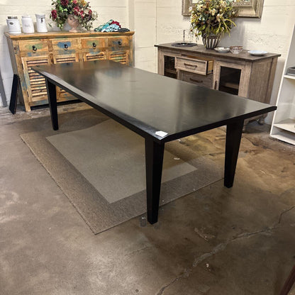 Black dining table in a room with wooden furniture and decorative items.