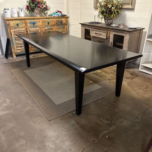 Black dining table in a room with wooden furniture and decorative items.
