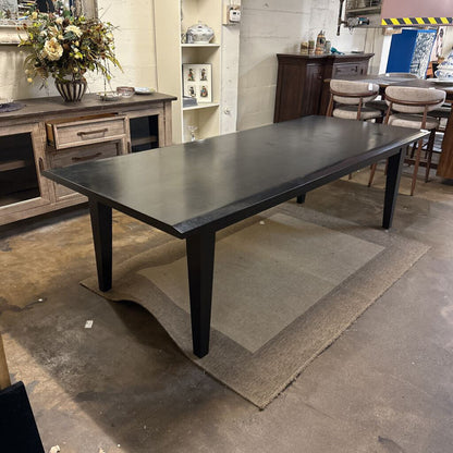 Large dark wooden dining table in a room with furniture and decor.