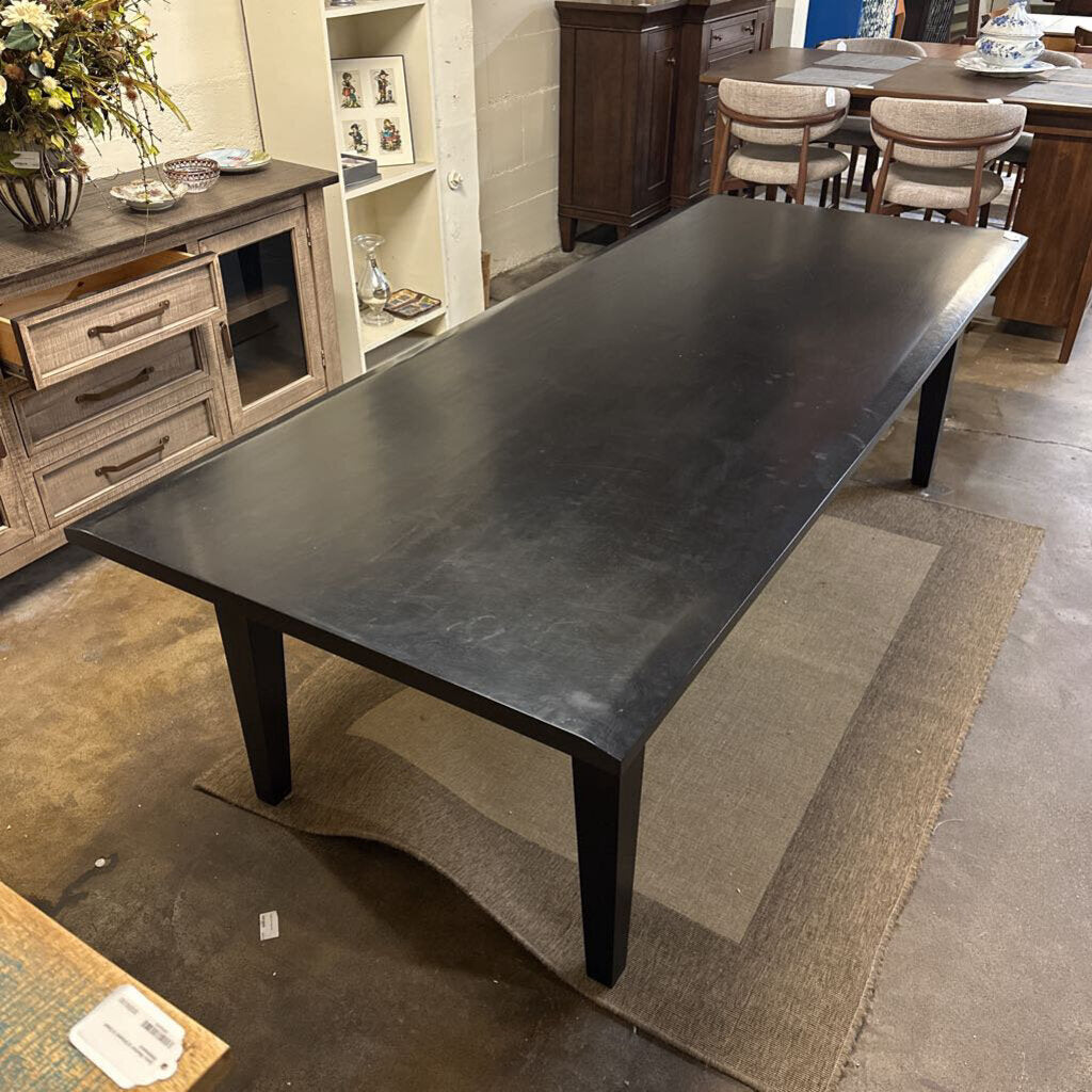 Large dark wooden dining table in a room with furniture and decor.