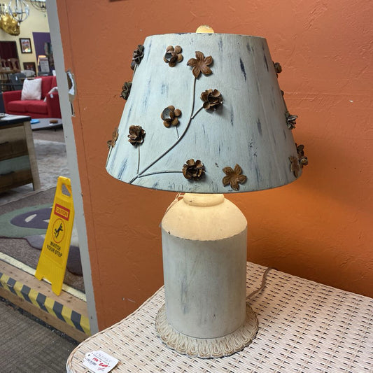 Decorative lamp with floral design on a table against an orange wall.