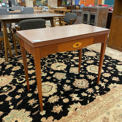 Wooden table with a decorative drawer on a patterned rug in an indoor setting