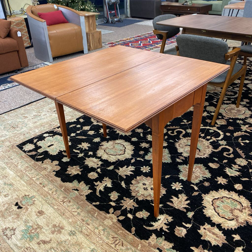 Wooden dining table on a patterned rug with chairs in the background