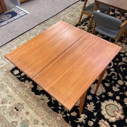 Wooden dining table with one leaf extended on a patterned rug