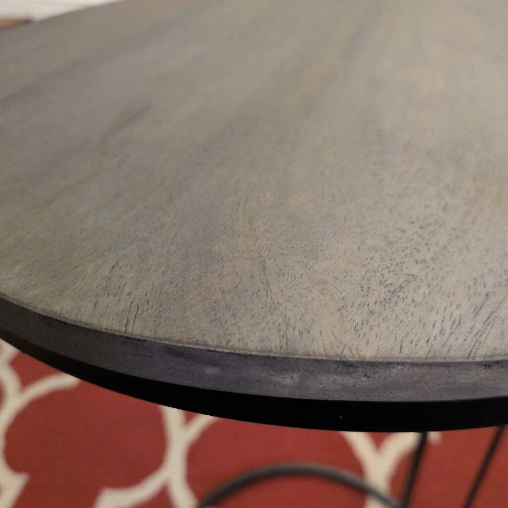 Round wooden table with a dark finish on a patterned red and white rug