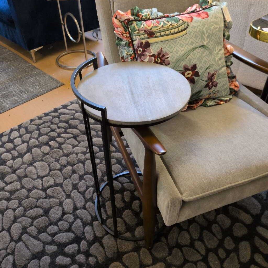 Small round table next to a chair with floral cushions on a textured rug.