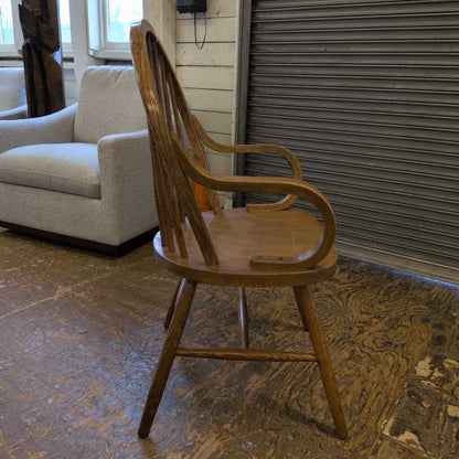 Wooden chair in a room with a beige sofa and a closed metal shutter.