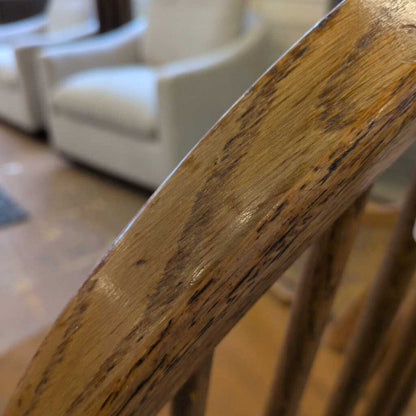 Close-up of a wooden chair arm with a blurred background of a living room.