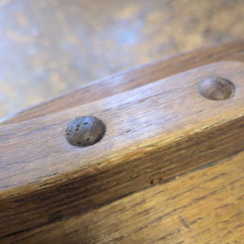 Close-up of a wooden handle with metal rivets on a blurred background