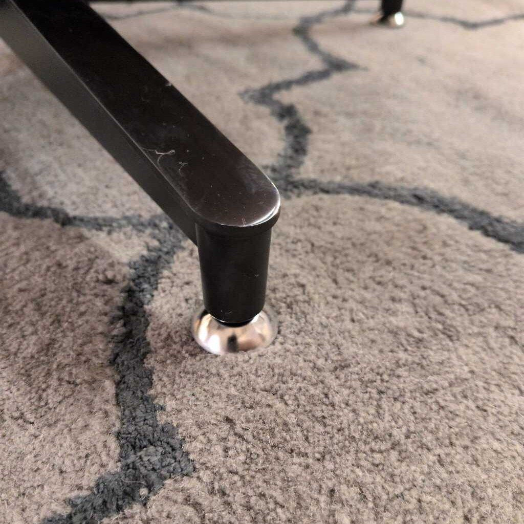 Close-up of a chair leg on a textured carpet