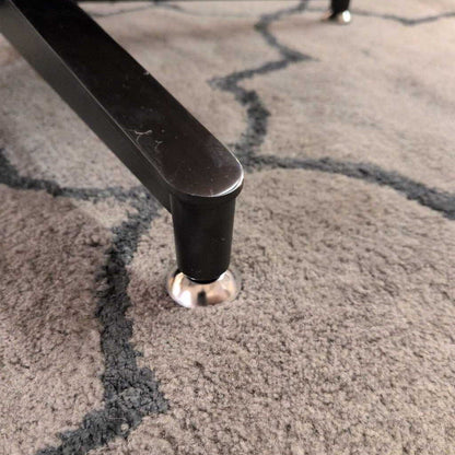 Close-up of a chair leg on a textured carpet