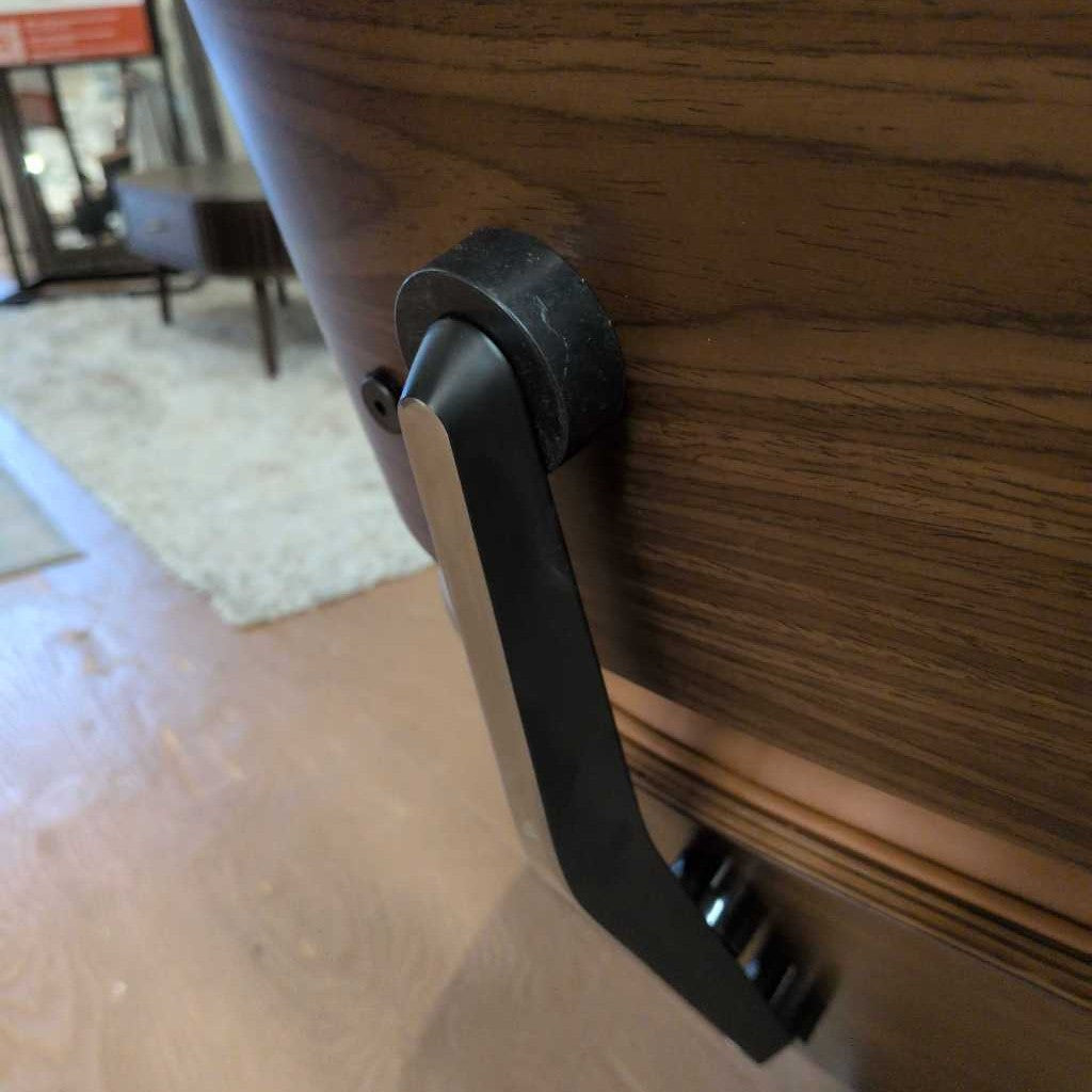 Black handle on a wooden door with a blurred indoor background