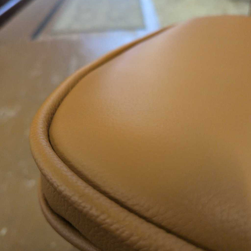 Close-up of a brown leather surface with a visible seam.