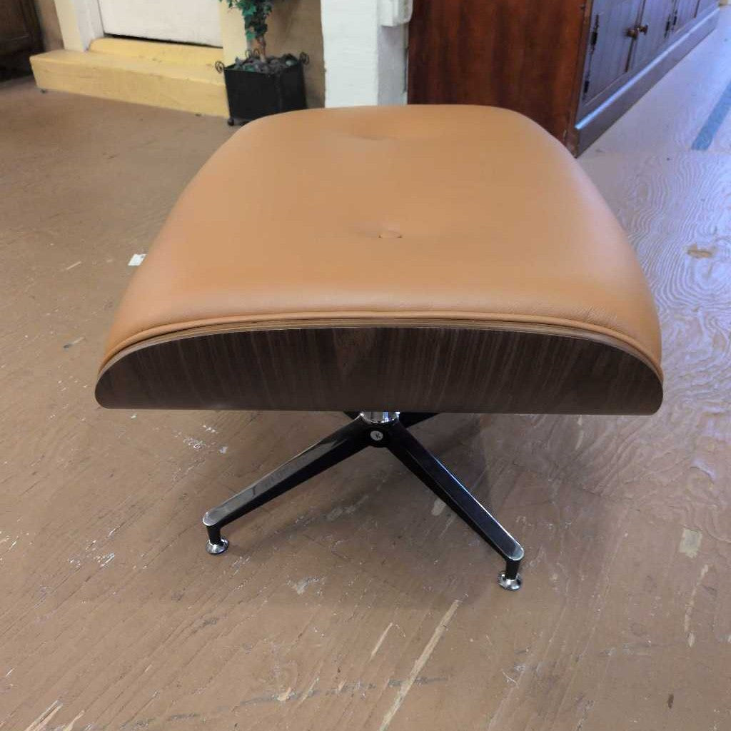 Brown ottoman with a black base on a wooden floor.