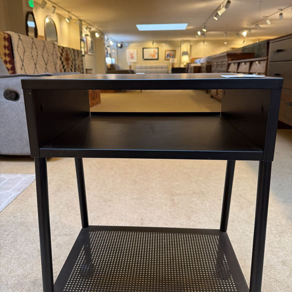 Black metal side table in a room with furniture and decor.