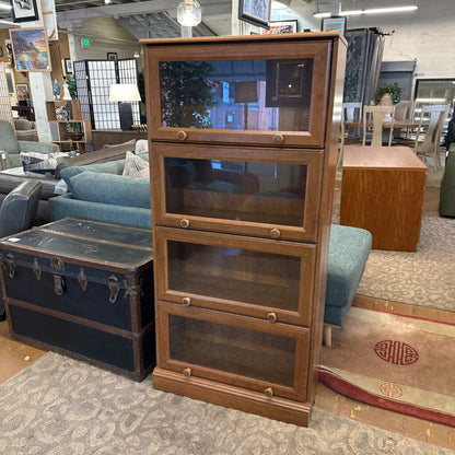 Wooden bookshelf with glass panels in a room with furniture and decor.