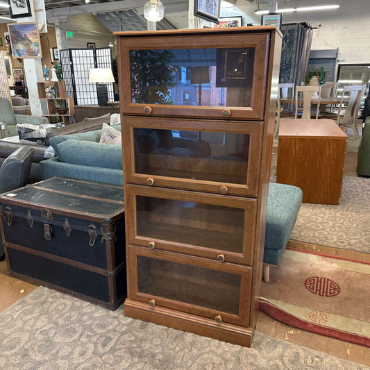 Wooden bookshelf with glass panels in a room with furniture and decor.