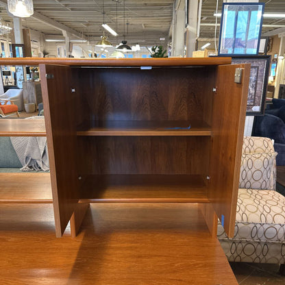 Wooden bookshelf in a store setting with furniture and decor in the background