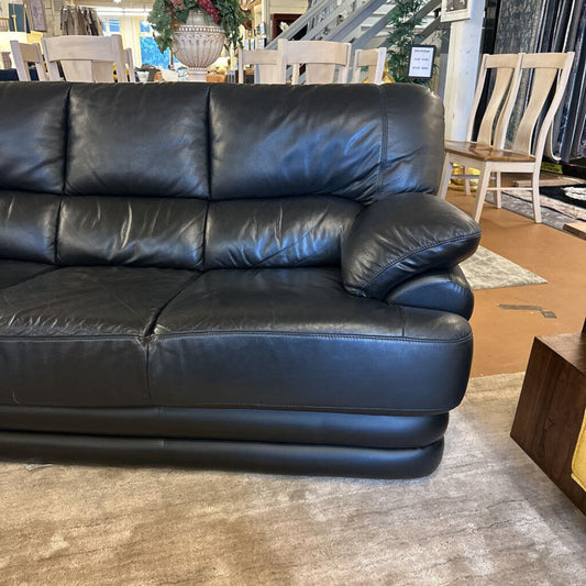 Black leather sofa in a room with chairs and decor