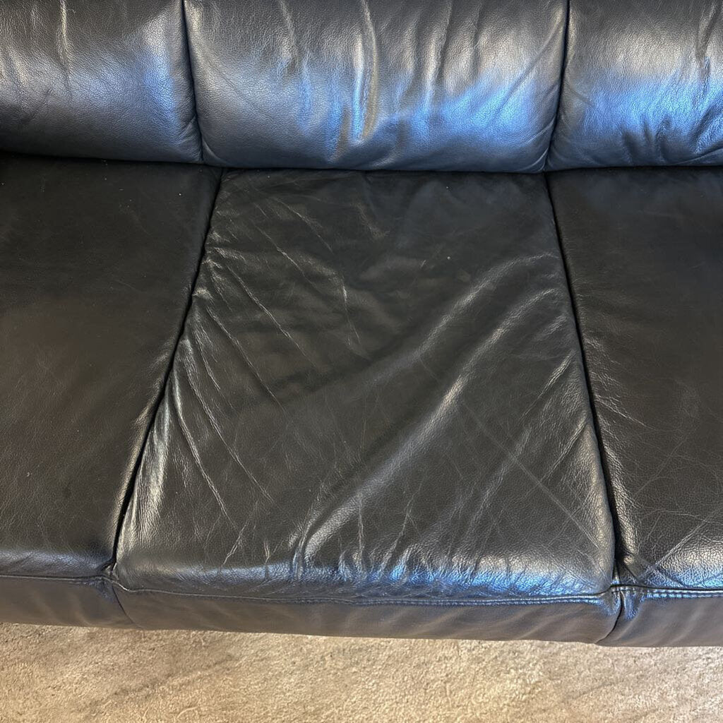 Black leather sofa with visible wear and tear