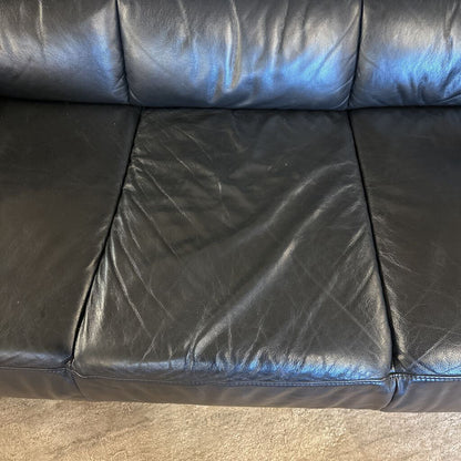 Black leather sofa with visible wear and tear