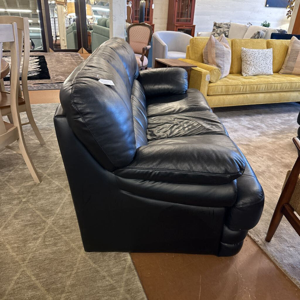 Black leather sofa in a showroom with other furniture in the background