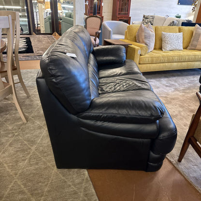 Black leather sofa in a showroom with other furniture in the background