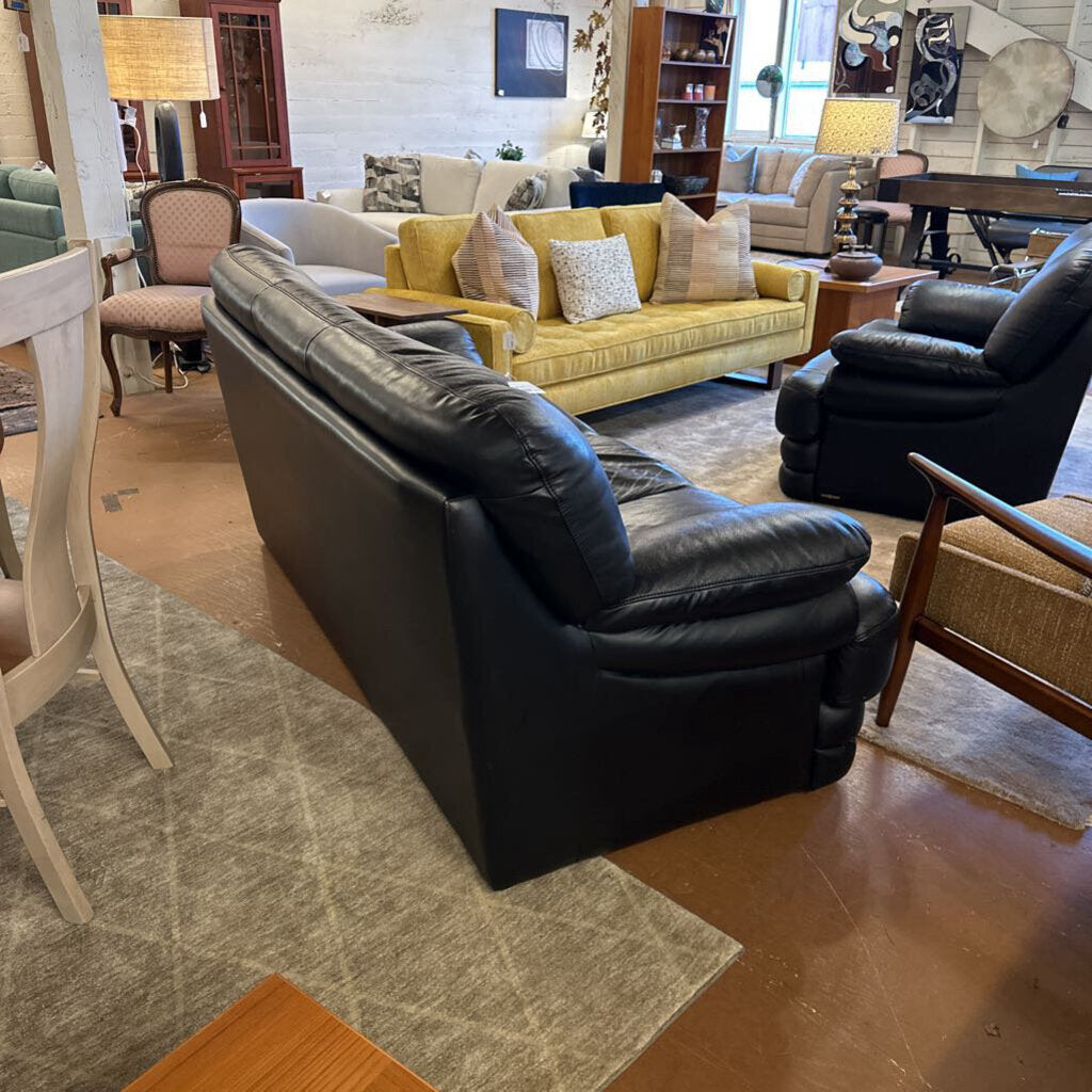 Living room with black leather sofa, yellow couch, and various furniture pieces.
