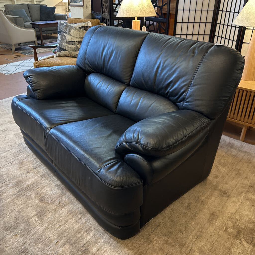 Black leather sofa in a living room setting with furniture and decor.