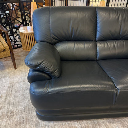 Black leather sofa in a room with furniture and decor.
