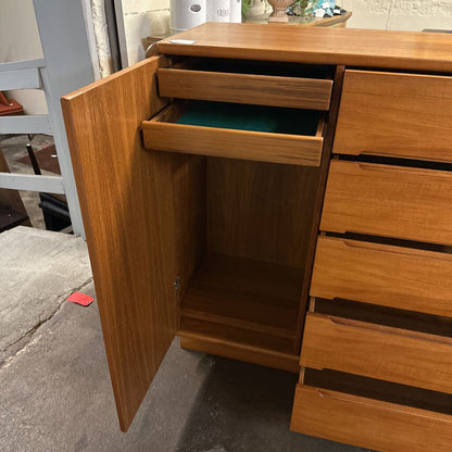 Wooden cabinet with an open door and drawers on a concrete floor.