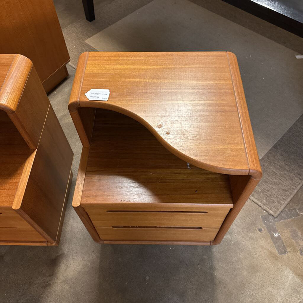 Wooden nightstand with a curved design on a concrete floor.