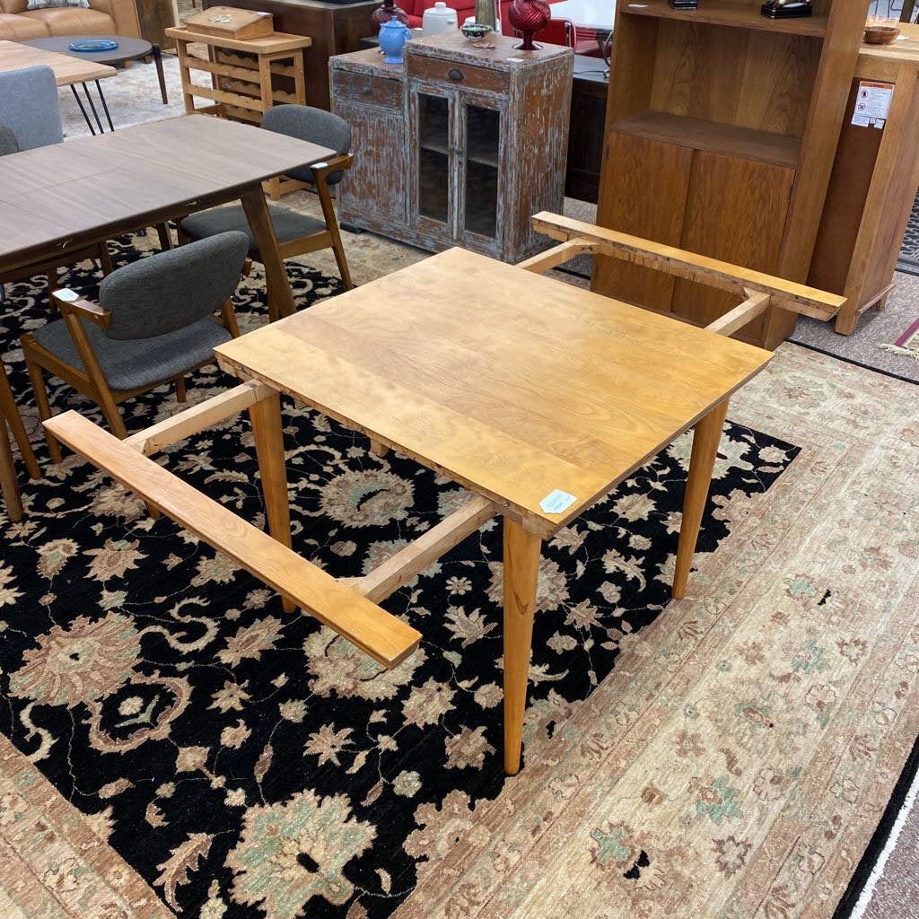 Wooden table with benches on a patterned rug in a furniture store setting