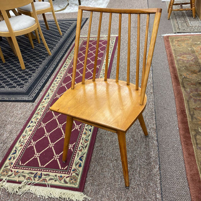 Wooden chair on a patterned rug with other chairs in the background