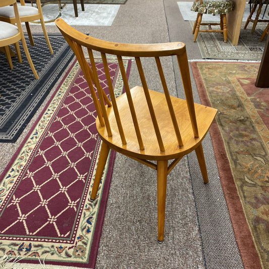 Wooden chair on a patterned rug with other chairs in the background