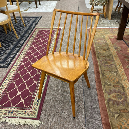 Wooden chair on a patterned rug with other chairs in the background