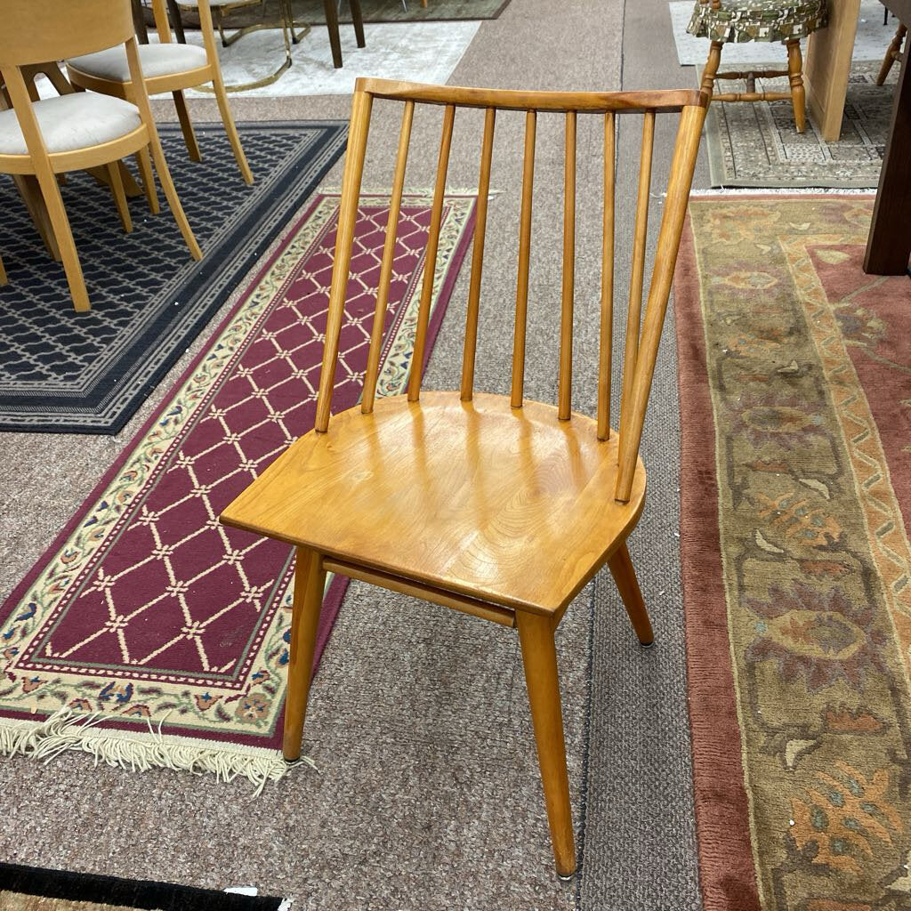 Wooden chair on a patterned rug with other chairs and furniture in the background