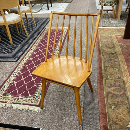 Wooden chair on a patterned rug with other chairs and furniture in the background