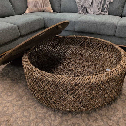 Round woven coffee table in front of a gray sectional sofa.