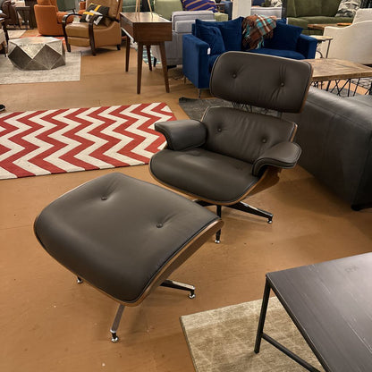 Modern gray lounge chair and ottoman in a living room setting with colorful rug and furniture.