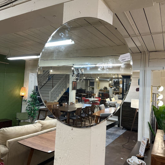 Large round mirror on a stand in an indoor setting with furniture and decor.