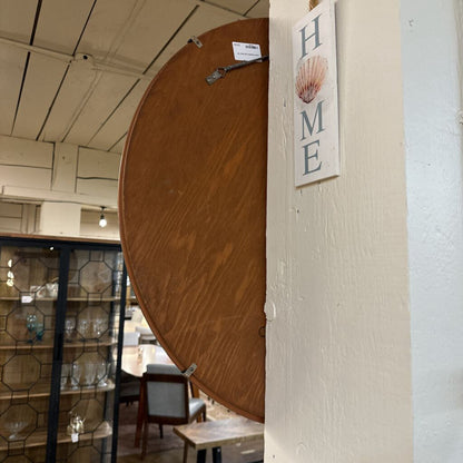Round wooden table with a 'HOME' sign featuring a shell design in a store setting.
