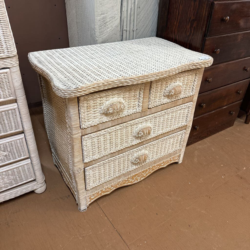 Wicker nightstand with three drawers on a brown floor.