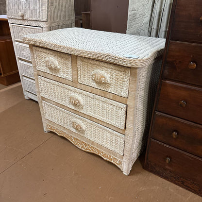 Wicker chest of drawers with decorative elements on a brown floor.
