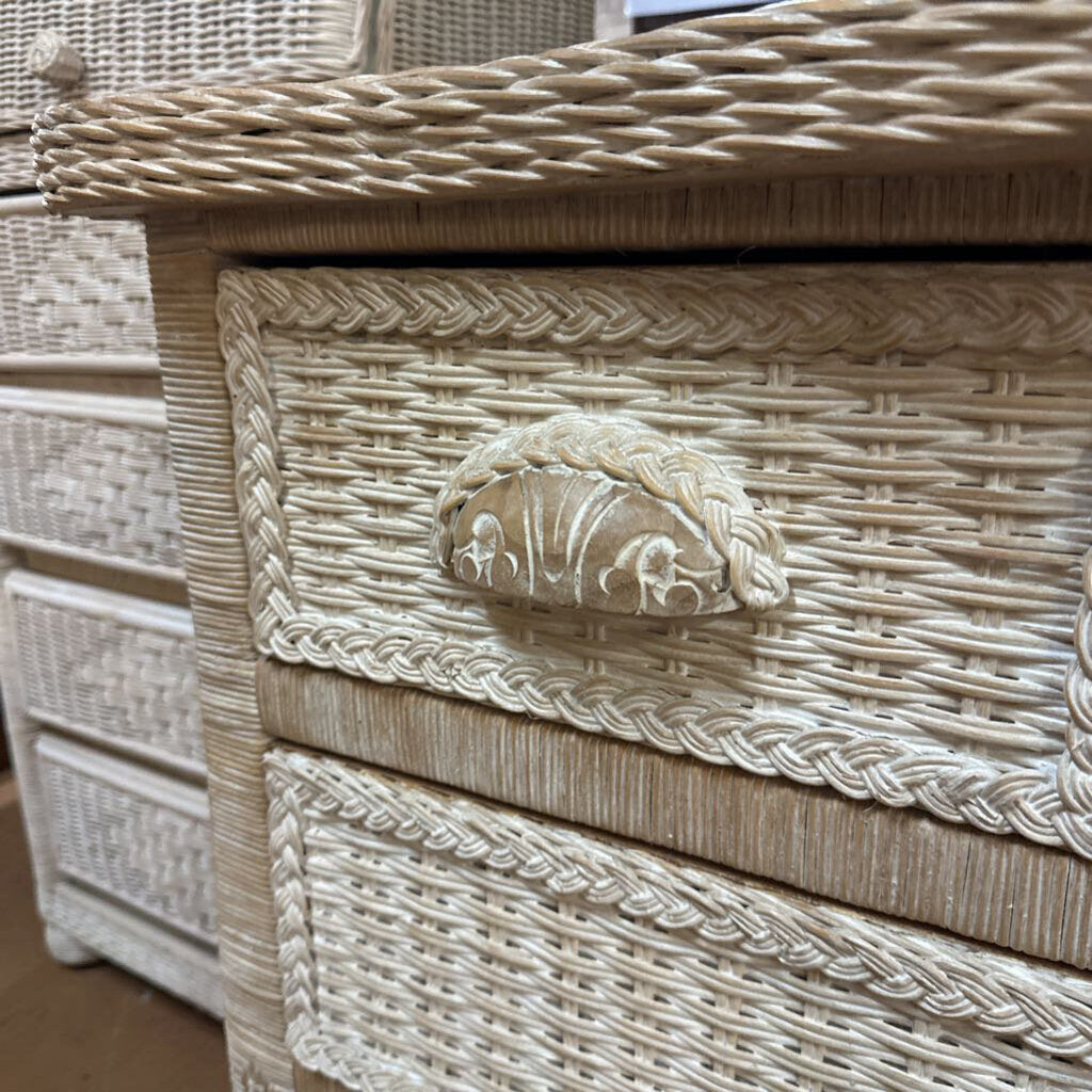 Wicker chest with decorative lion head handle on a wooden floor.