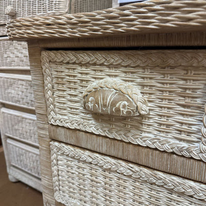 Wicker chest with decorative lion head handle on a wooden floor.