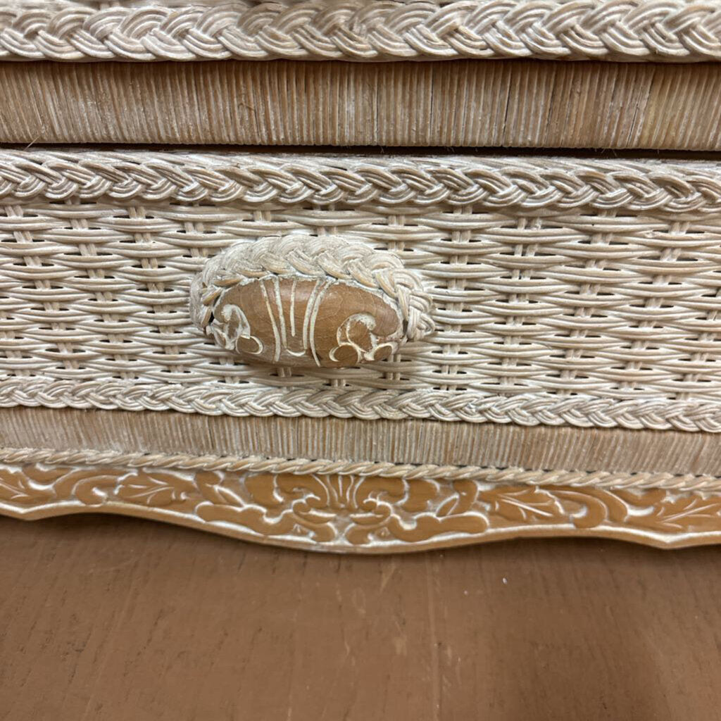Decorative woven box with intricate patterns and a central emblem on a wooden surface.