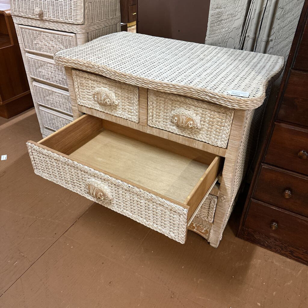 Wicker side table with open drawer in a store setting